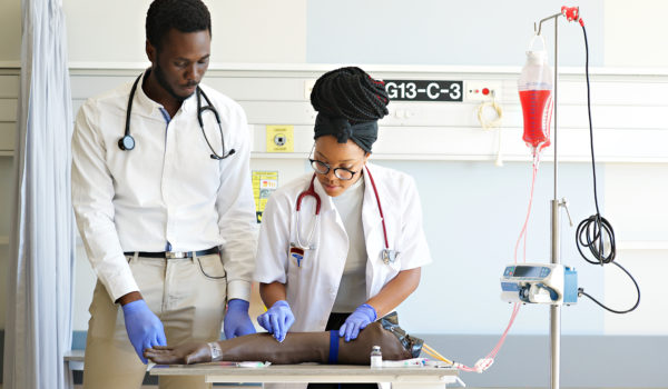Female Student practising IV injection on a Phlebotomy Venipuncture Practise Arm Students practising IV injection on a Phlebotomy Venipuncture Practise Arm with a medical instructor teaching the correct way in a University Hospital in Cape Town South Africa